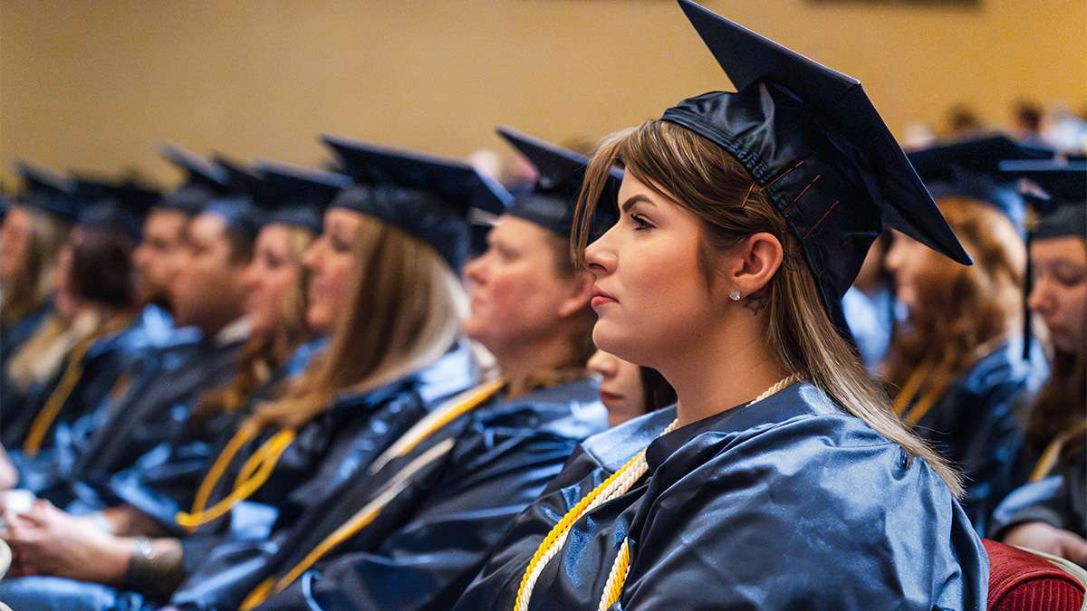 A group of graduating students wearing blue and gold colored academic regalia.