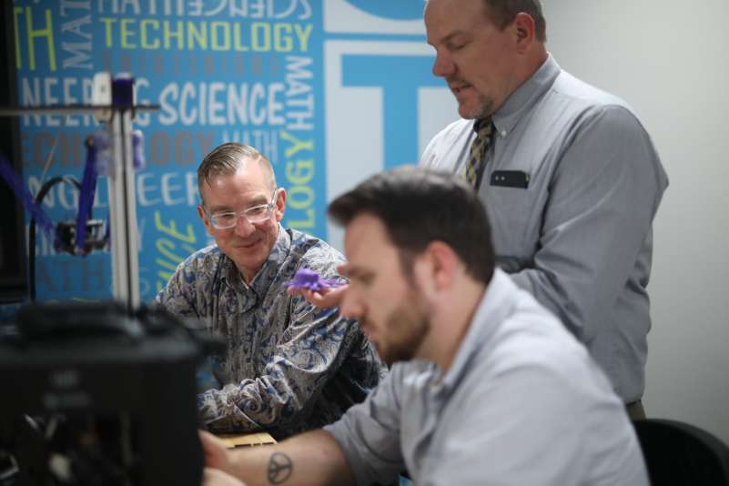 Two students, seated, listen to instructor explaining something.