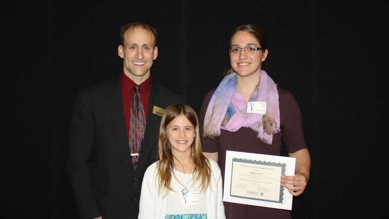 Brad Gast stands next to a student who received the Scott and Lucas Gast Scholarship. A young girl stands in front of them.