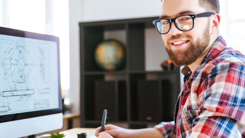 A man is working at a computer with a pen in his hand