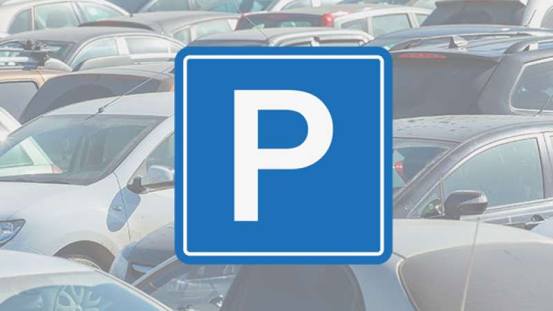 A blue sign with the letter P is overlayed on top of an image of a parking lot full of vehicles