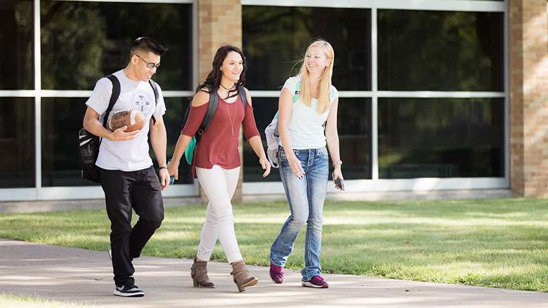 Three students are walking together in the NTC Courtyard