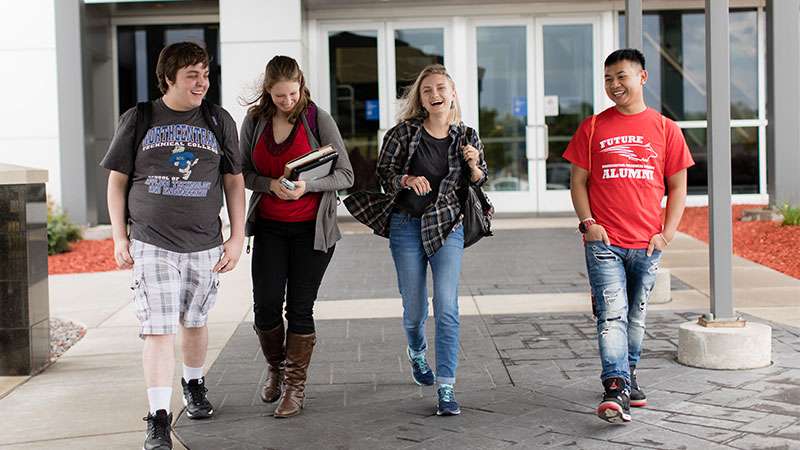 Four students walking together near front entrance of NTC