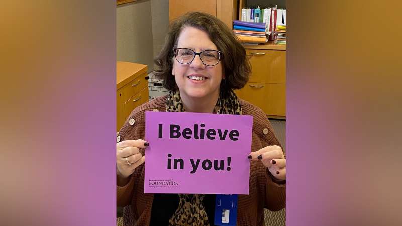 Jeannie Worden holding a sign that reads: I believe in you!