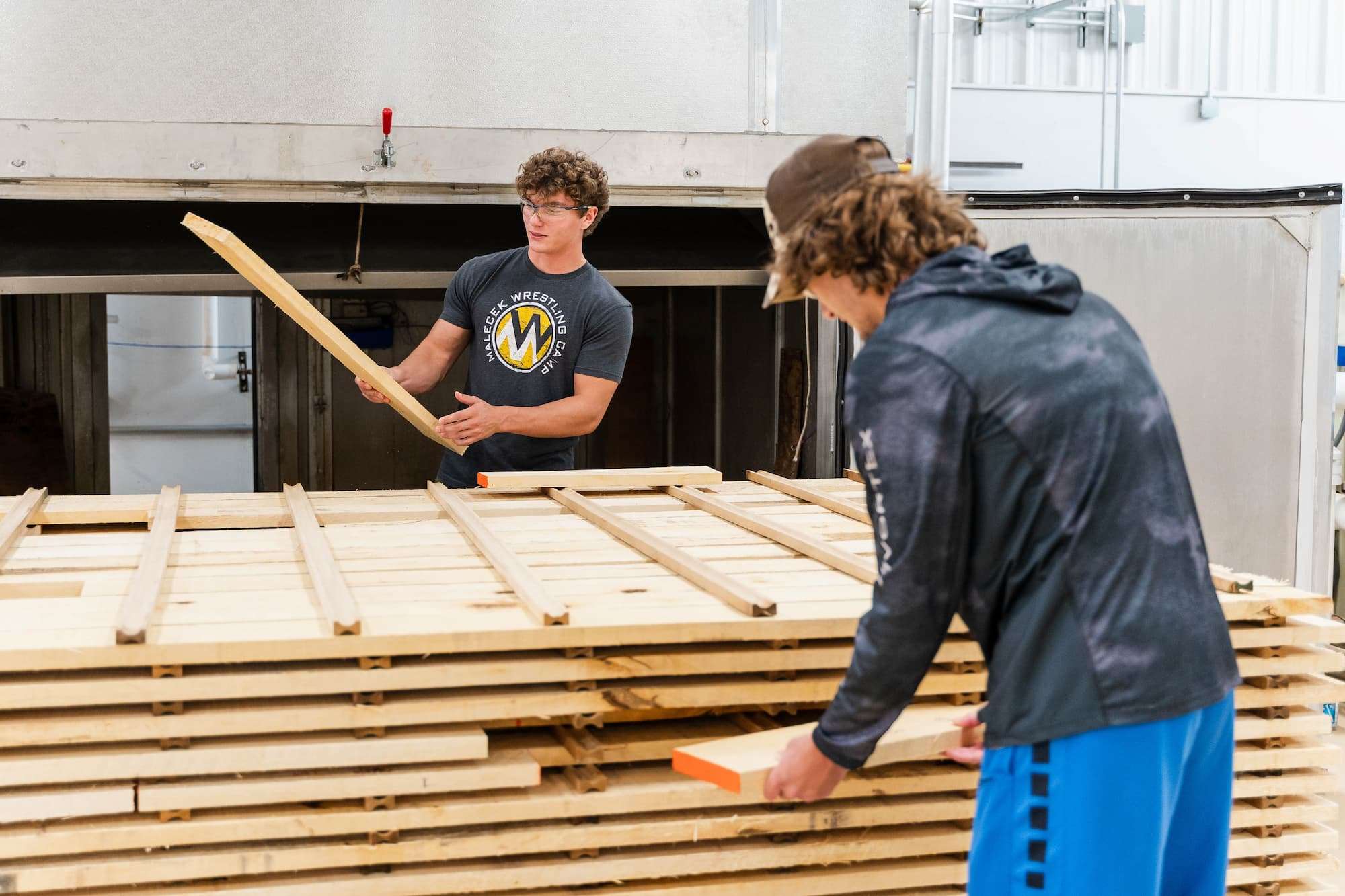 Two students examine lumber that is about to be moved into a kiln.