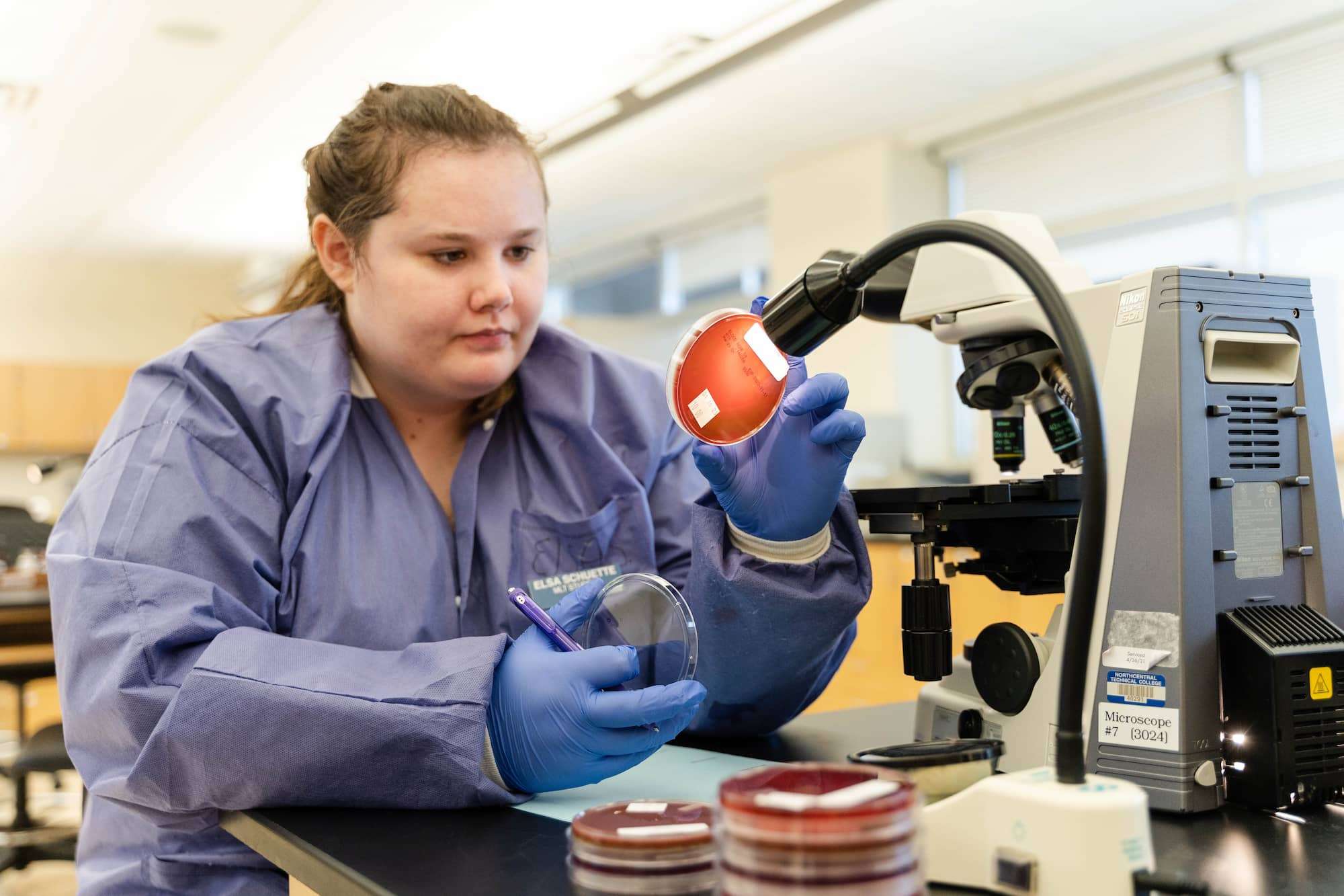 While examining microbiology samples, a student takes notes on her findings.