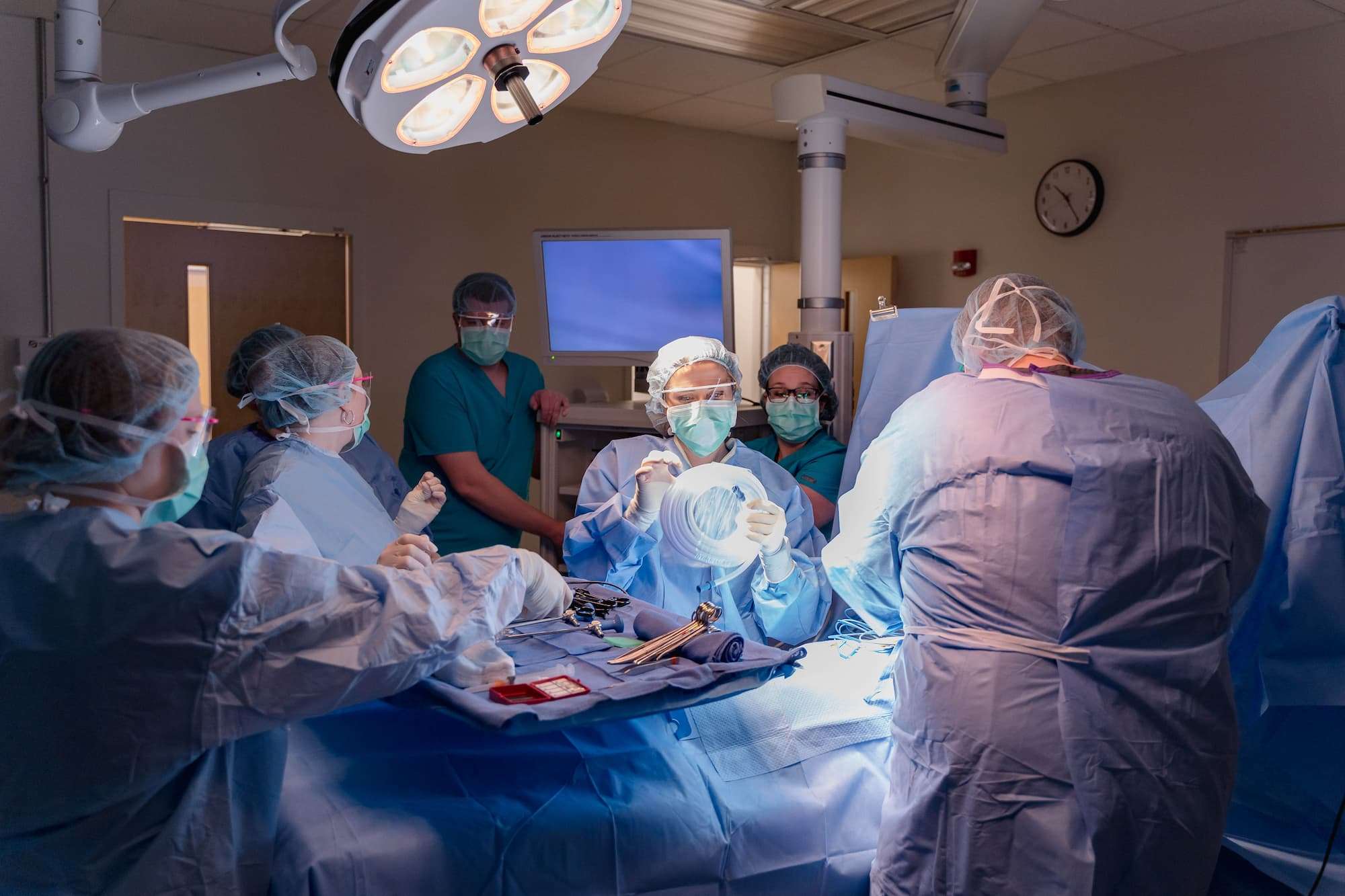 A large group of surgical technology students coordinate a mock operation.