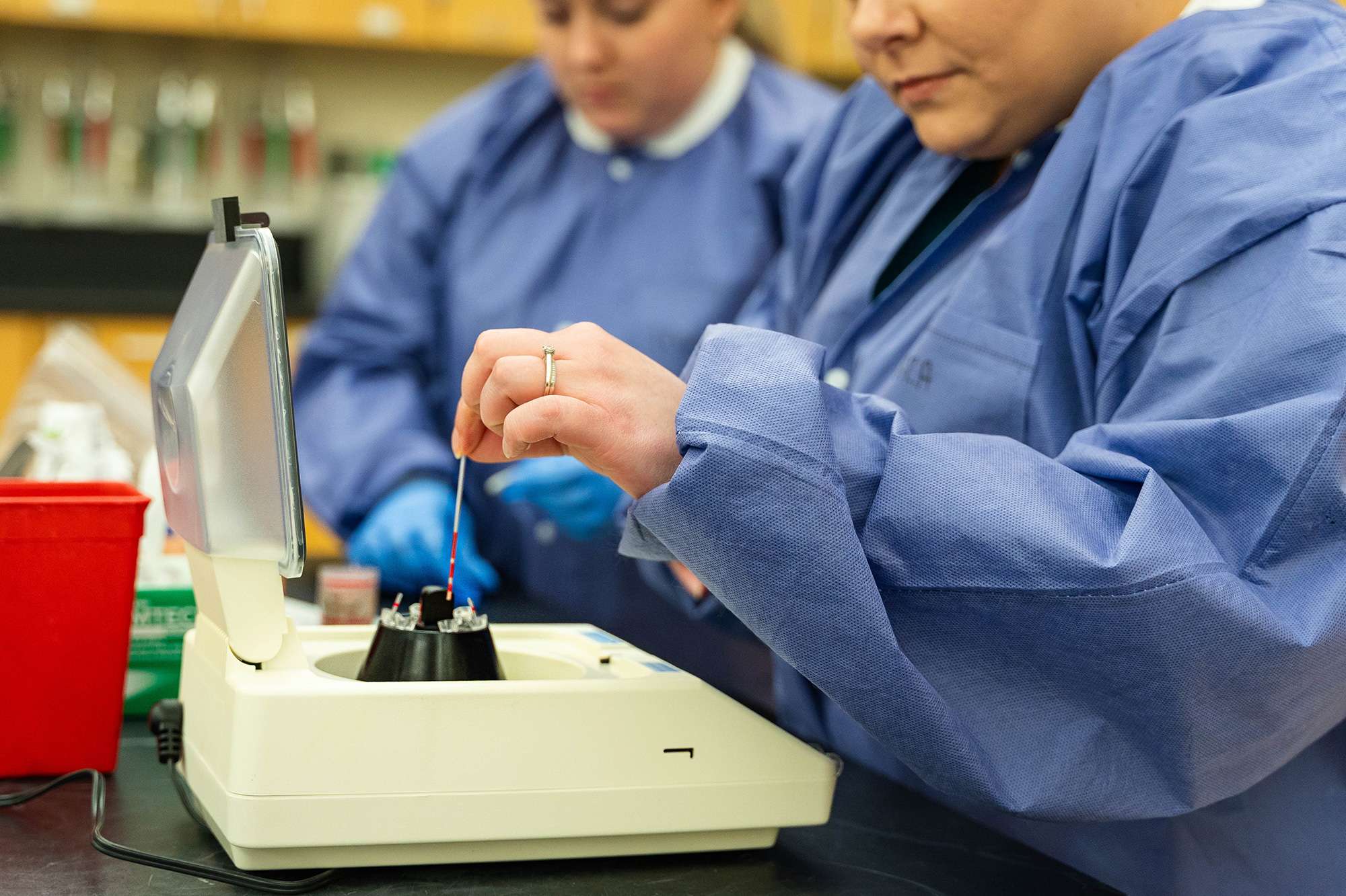 Two Medical Assistants work together to check a patient's blood work in a lab.