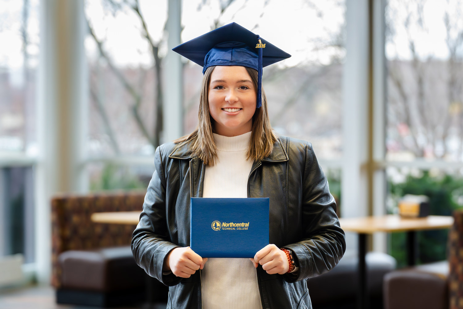 Hannah posing while wearing an NTC graduation cap and holding his diploma.