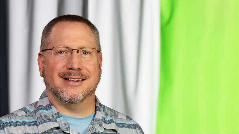 Rex Anderson posing in front of a multi-colored backdrop