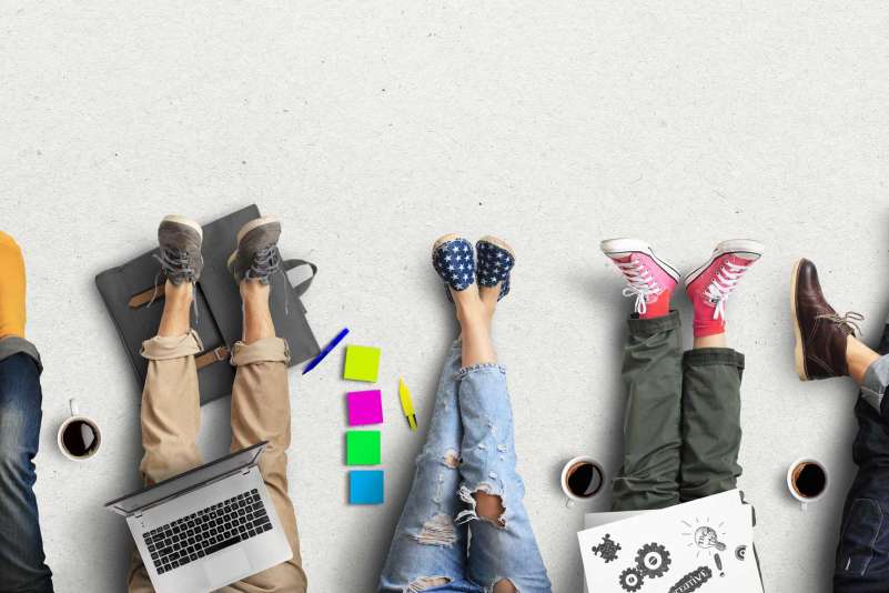 Legs and feet of students studying, with their materials on their laps and coffee mugs next to them.