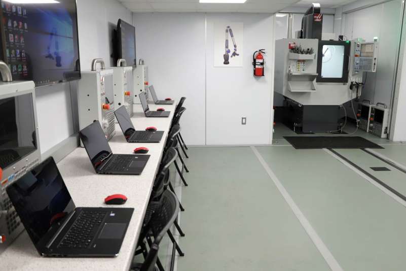 Several laptops and other equipment sitting on a table along the wall in the Advanced Manufacturing Mobile Lab