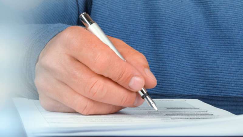 A person is writing down information on a report