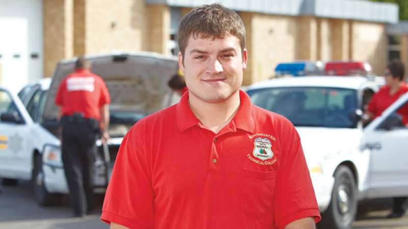 An NTC Security team member stands in front of a two squad cars