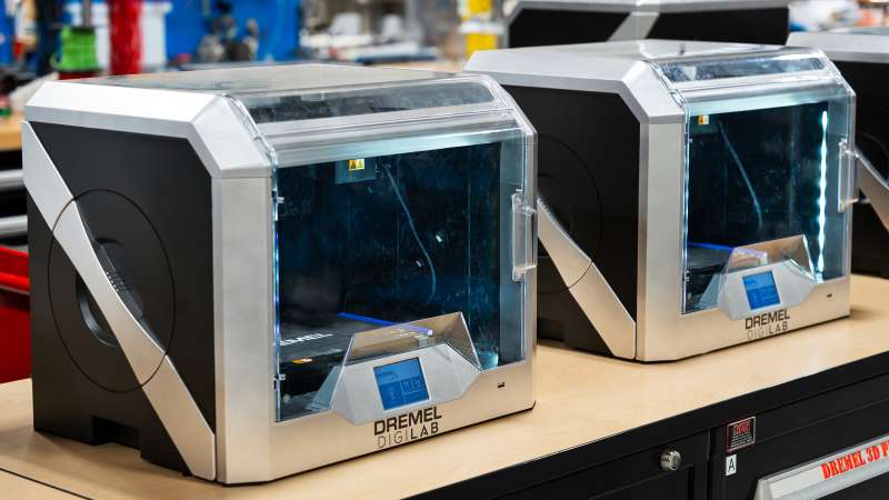 Two Dremel DigiLab 3D printers on a workbench in the Mechatronics & Fluid Power Lab. The printers are enclosed with clear front panels and digital interfaces, designed for precise additive manufacturing in an educational or prototyping setting.